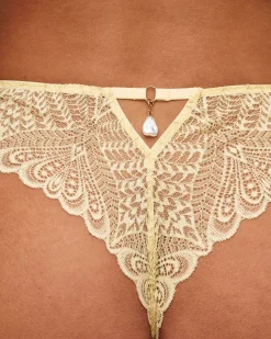 Tanga en dentelle avec fil lurex doré et bijou